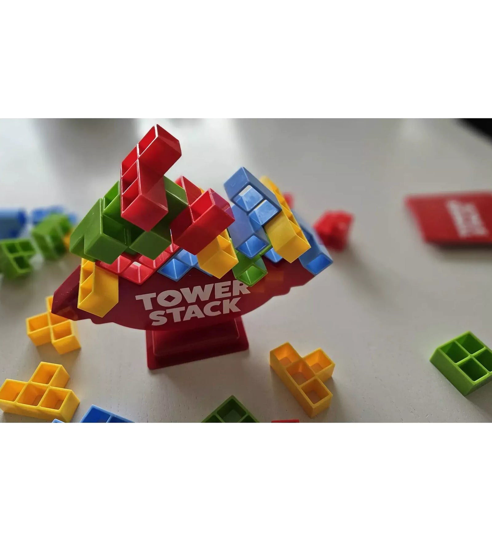 Tower Stack játék közben, színes piros, zöld, kék és sárga elemek egyensúlyoznak a piros alapra épített tornyon.