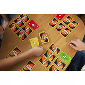 Az UNO Zero játék közbeni jelenet, ahol több játékos kártyázik egy faasztalnál. A játékosok UNO Zero hátlapú és számozott, színes kártyákkal játszanak, látható köztük sárga 6-os és zöld 0-s lap is.